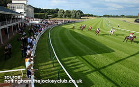 The Grandstand at Nottingham Racecourse with a race taking place in the foreground