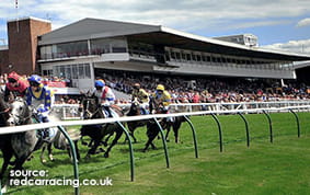 The Grandstand at Redcar Racecourse with a horse race taking place