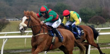 Two brown horses with riders racing on a track